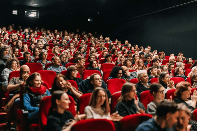 Zdjęcie pełnej sali kinowej. Zgłoś swój film na 26. MFF WATCH DOCS. Termin zgłoszeń 31 sierpnia. Warszawa + Online 4-13 grudnia, 2026